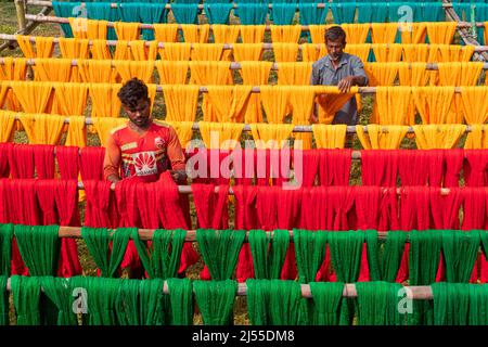 Narayanganj, Dhaka, Bangladesh. 20th Apr, 2022. Workers hang thousands of freshly dyed colorful threads on a wooden structure as they are being dried in the sunshine in Narayanganj, Bangladesh. Thousands of colorful threads create a palette of colors as workers hang them out to dry. The threads take a whole day to dry and stretch for hundreds of meters. Once dried, they are sold to wholesale markets. Each row of threads is priced for £2. The workers spend 12 hours in the fields during this process, earning £5 per day. (Credit Image: © Joy Saha/ZUMA Press Wire) Stock Photo