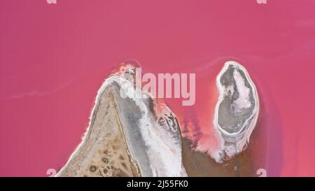 Flying over a pink salt lake. Salt production facilities saline evaporation pond fields in the salty lake. Dunaliella salina impart a red, pink water Stock Photo