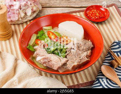 Stewed Pork Ribs Noodles in a bowl with spoon and chopsticks isolated on mat side view on wooden table taiwan food Stock Photo