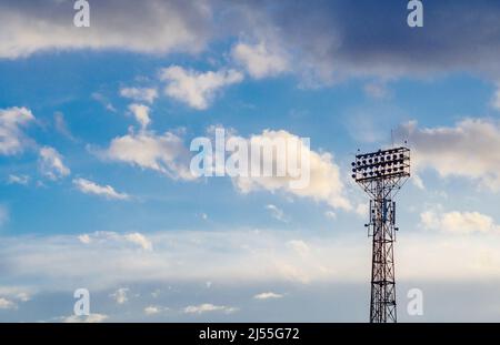 Stadium spotlight set on  background of blue sky. Cumulonimbus. Stock Photo