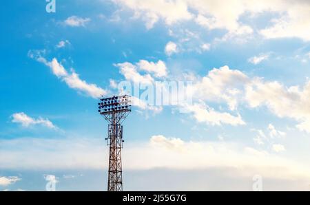 Stadium spotlight set on  background of blue sky. Blue sky with white clouds. Stock Photo