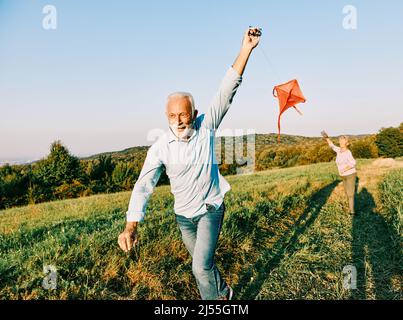 woman man outdoor senior couple happy lifestyle retirement together smiling love kite run nature mature Stock Photo