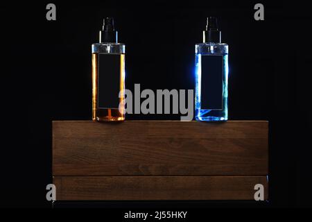 two bottles with yellow and blue liquid. two spray spraying cans on black background on wooden stand. mockup on cans, jars. selective focus. barbersho Stock Photo