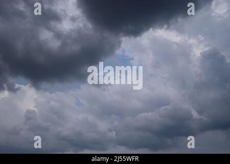 white and some dark clouds in the sky. Natural Dramatic Clouds. Black cloudy and dark sky before heavy rainy and storm coming. Low stormy clouds for a Stock Photo