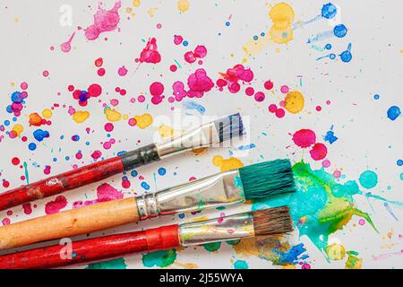Artist paint brushes on background of colorful watercolor splashes, vivid blots, drops Stock Photo