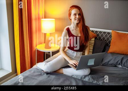 Woman using a laptop in the night sitting on a couch in the bad room at home Stock Photo