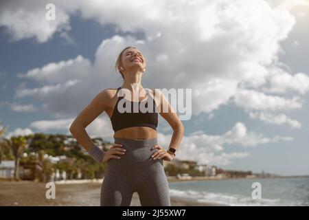 Young sportswoman relaxing while standing on beach Stock Photo