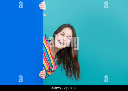 laughing kid behind blank blue paper with copy space for advertisement Stock Photo