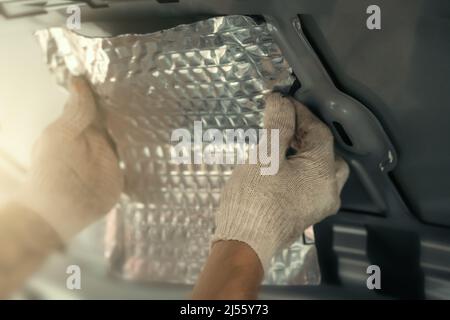 Worker installing special acoustic and vibration-damping material for noise insulation. Soundproofing, auto tuning. Stock Photo