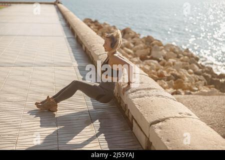 Model listening to music during exercising near sea Stock Photo