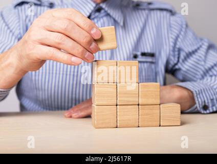 Man building career ladder from wooden blocks. Professional development and personal growth. Promotion, success and goals achievement in work. High quality photo Stock Photo