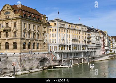 Basel, Switzerland - April 2022: Buildings on the Rhine River in the centre of the city showing the facade of the luxury Grand Hotel Les Trois Rois. Stock Photo