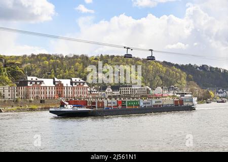 Koblenz, Germany – April 2022: Industrial barge transporting shipping containers on the Rhine River passing underneath cable cars Stock Photo