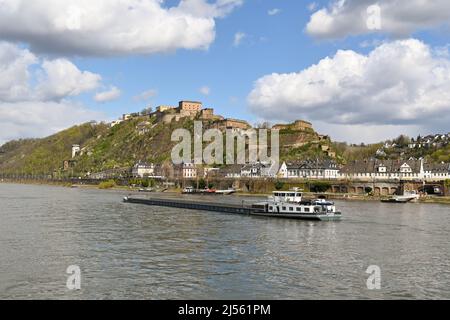 Koblenz, Germany – April 2022: Industrial barge sailing through Koblenz on the Rhine River. In the background is the town's hilltop fortress. Stock Photo