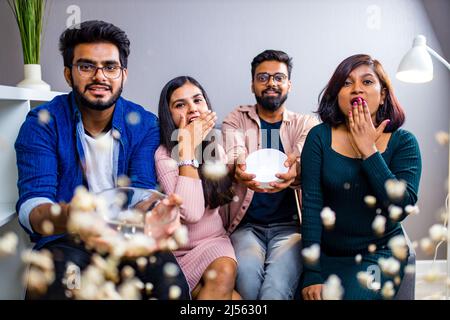 four indian friends watching cinema in the night time at home throwing popcorn Stock Photo