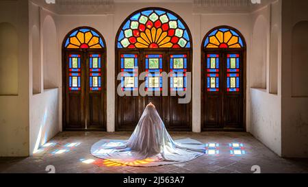 Kashan, Iran - May 2019: Unidentified Iranian woman in chador hijab praying inside Tabatabaei Natanzi Khaneh Historical House Stock Photo