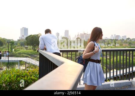 couple watching the cityscape with skyscrapers from a park at sunset Stock Photo