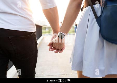 Couple holding hands outdoors during sunset Stock Photo