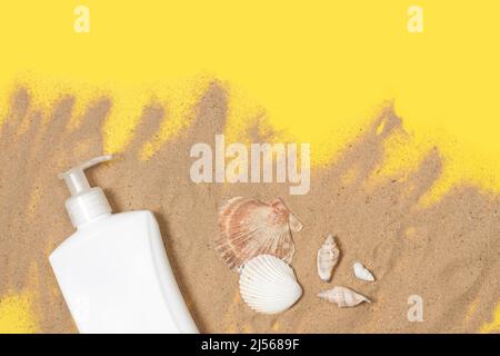A sun tan lotion bottle and seashells on sand and on a yellow background Stock Photo