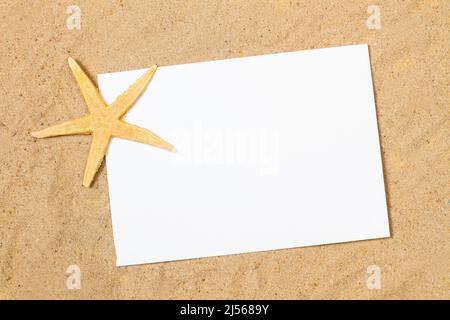 A yellow starfish with a blank white paper on the sand with copy space Stock Photo