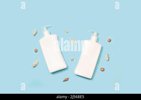 Sun tan lotion bottles and seashells on a light blue background Stock Photo