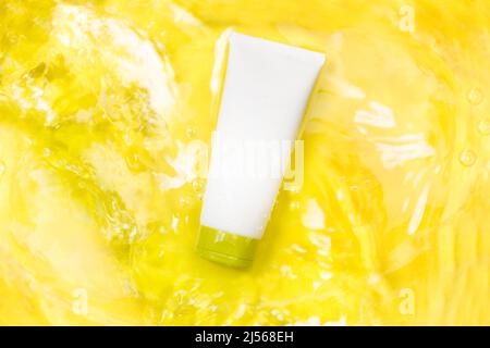 Moisturizer cream soft tube over the water on a yellow background in a top view Stock Photo