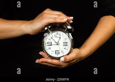 Woman holding an alarm clock with her both hands Stock Photo