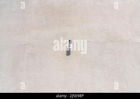 Lone security camera on a wall at San Jose, California. Wall-mounted surveillance camera in the middle of a concrete wall at the background. Stock Photo