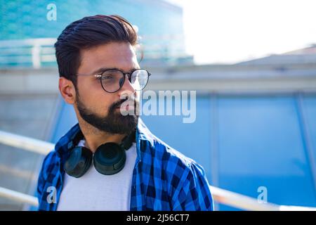 handsome bearded brunette arabian man listen musics outdoor street Stock Photo