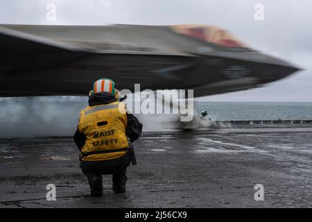 SEA OF JAPAN (April 14, 2022) Aviation Boatswain’s Mate (Equipment) 2nd Class Kayla Pettit, from Charlotte, N.C., signals an an F-35C Lightning II, assigned to the 'Black Knights' of Marine Fighter Attack Squadron (VMFA) 314, as it launches from the flight deck of the Nimitz-class aircraft carrier USS Abraham Lincoln (CVN 72) during a U.S.-Japan bilateral exercise. During bilateral exercises between Abraham Lincoln Carrier Strike Group and Japan Maritime Self-Defense Force, the two navies strengthen all-domain awareness and maneuvers across a distributed maritime environment. Bilateral operati Stock Photo