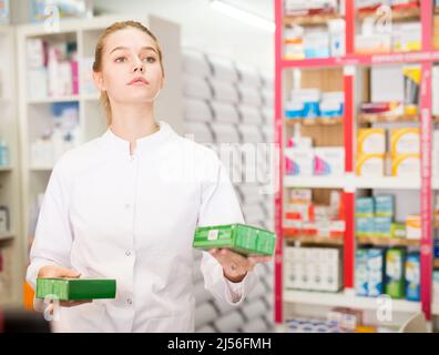 Young friendly female pharmacist suggesting useful tablets in pharmacy Stock Photo
