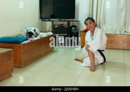 A woman wearing a white kimono with a black belt at home. Stock Photo