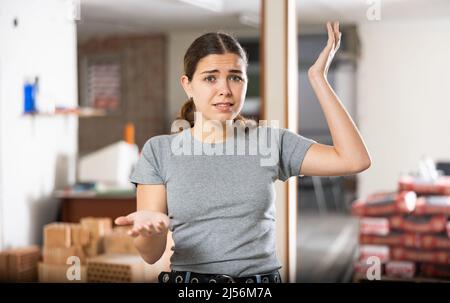 Puzzled young woman examining her house during renovation Stock Photo