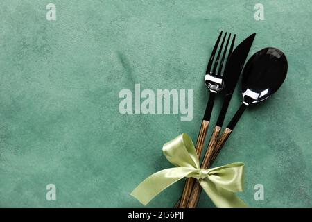 Cutlery with ribbon on green background Stock Photo