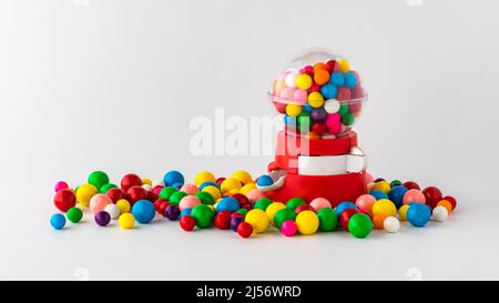 A plastic toy gum ball machine filled and surrounded by gum balls.