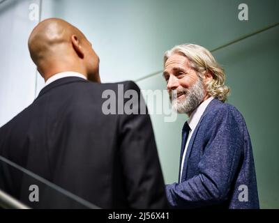 caucasian and latino corporate business men talking chatting having a conversation while walking on stairs in modern office building Stock Photo