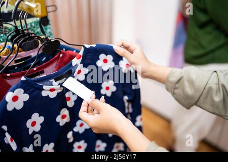 gesture of female's hand looking at price tag at fashion store Stock Photo