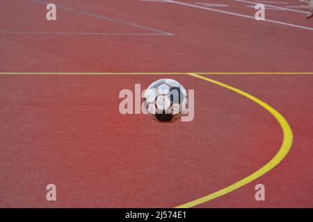 Soccer ball football flying over a sports court with yellow and red Stock Photo