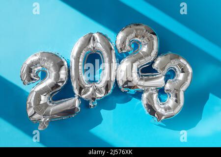 Happy New year 2023 celebration sunshine's bright light. Silver balloons figures, New Year Balloons Christmas and new year celebration. Silver foil ba Stock Photo