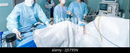 Surgeons operate on the patient in the operating room. A team of doctors performs laparoscopic surgery. Widescreen image. Banner. Stock Photo
