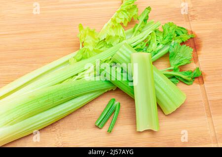Fresh Celery Stem and Chopped Celery Sticks on Wooden Cutting Board. Vegan and Vegetarian Culture. Raw Food. Healthy Diet with Negative Calorie Content. Slimming Food Stock Photo