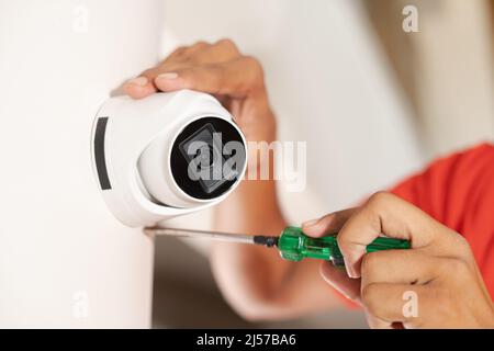 Close up shot of technician fixing cctv camera on wall at home - concept of safety, professional worker and maintenance service Stock Photo