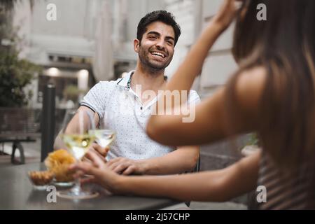 Couple celebrating in outdoor cafe and having a glass of white wine - focus on man face - unrecognizable woman - alcohol, dating and lifestyle concept Stock Photo
