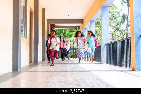 Enjoying group of kids running at school corridor for going to classroom - concept of education, reopen school, active childhood and learning. Stock Photo