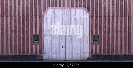 Old wooden facade with purple stripe pattern and a large gate Stock Photo