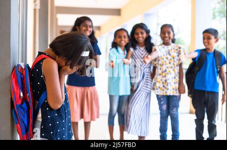 Girl kid being bullied by group of children at school corridor - concept of rejection, innocent and victim Stock Photo