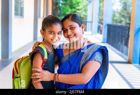 happy smiling Mother embracing her daughter before going to classrrom at school corridor by looking at camera - concept of back to school Stock Photo