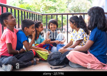 group of teenger children talking with friends while sitting at school campus during break time - concept of communication, conversation and childhood Stock Photo