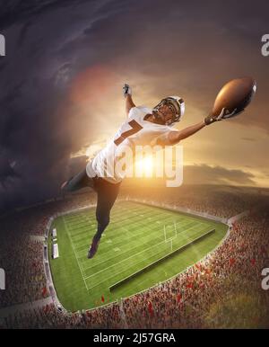 American football players catching ball in flight overt stadium with flashlights at evening time. Concept of sport, movement, achievements, leadership Stock Photo