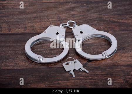 handcuffs with keys close-up on a dark wooden background Stock Photo